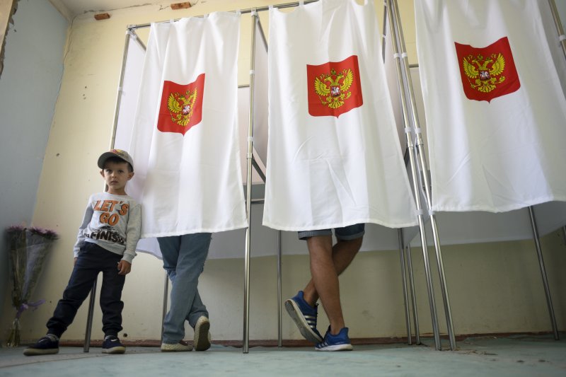 俄國18日舉行第7屆國家杜馬選舉，一位克里米亞男孩正在等待親人完成投票。（美聯社）