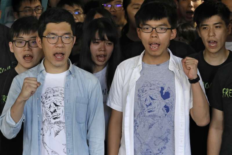 香港「雙學三子」黃之鋒(右)、羅冠聰(左)及周永康3年前發起「重奪公民廣場」開啟雨傘運動。(AP) 香港「雙學三子」黃之鋒(右)、羅冠聰(左)及周永康3年前發起衝擊「公民廣場」,開啟雨傘運動。2017年8月17日,3人遭判刑入獄,黃之鋒半年、羅冠聰8個月、周永康7個月。(AP)