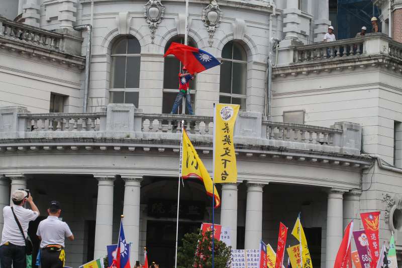 20180423-監督年金改革行動聯盟423抗爭活動，來自全國各地軍公教警消勞團體參與，一位抗議人士爬上監察院二樓頂拆揚國旗，稍後被警方帶走。（陳明仁攝）