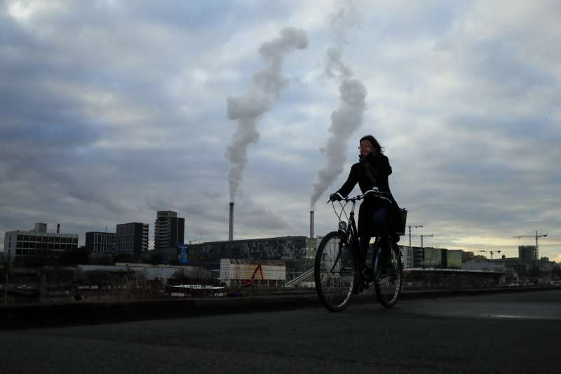 2018年12月4日，巴黎街頭一位女子騎著腳踏車經過排放黑煙的工廠。全球暖化，碳排放。(AP)