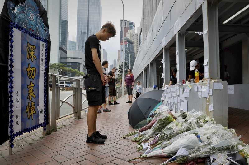 2019年6月15日，一名身穿雨衣的反送中示威者在金鐘太古廣場懸掛橫幅，要求香港政府全面撤回《逃犯條例》，不幸墜樓身亡，許多民眾至事發現場獻花悼念。(AP)