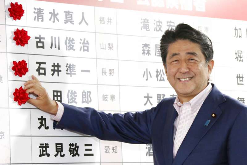 執政聯盟在參院大選中順利過半，安倍晉三為當選議員貼上紅花。（美聯社）