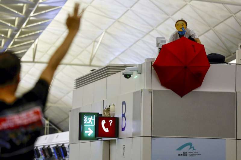 抗議「反送中」與「爆眼少女」的群眾連續第二天現身香港國際機場,癱瘓離境大廳與機場運作。(美聯社) 抗議「反送中」與「爆眼少女」的群眾連續第二天現身香港國際機場,癱瘓離境大廳與機場運作。(美聯社)