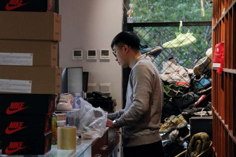 跟朋友一起經營運動鞋商店的管添在檢查庫存。 圖片來源:RAFFAELE HUANG/THE WALL STREET JOURNAL 跟朋友一起經營運動鞋商店的管添在檢查庫存。 圖片來源:RAFFAELE HUANG/THE WALL STREET JOURNAL