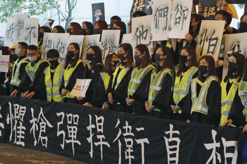 香港中文大學畢業生在2019年11月7日的畢業典禮上戴口罩手舉標語橫幅抗議。（美聯社）