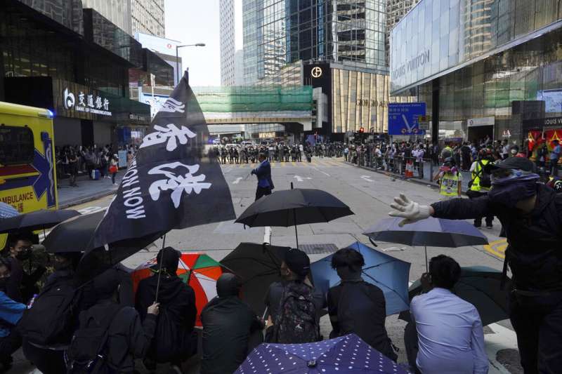 香港「反送中」抗爭者（持雨傘的群眾）11日在街頭與警察對峙。（美聯社）