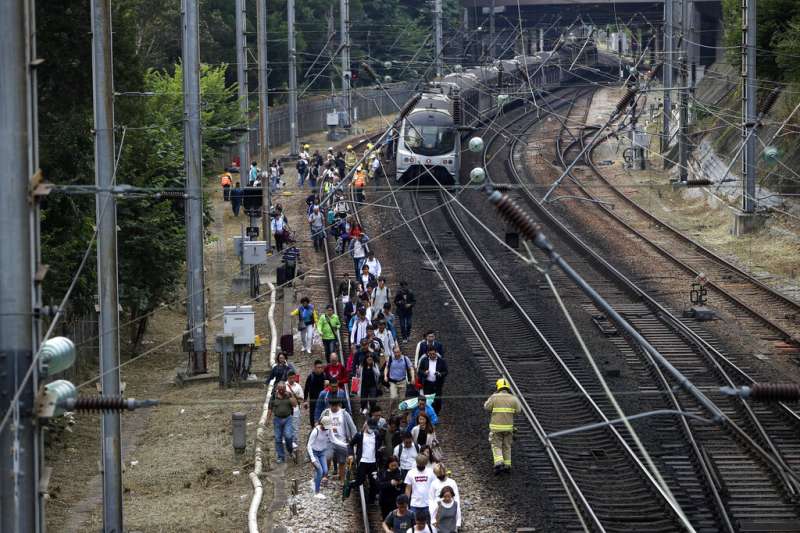 由於列車電纜遭到干擾、鐵軌附近也被投擲雜物,香港列車被迫停駛,乘客只能徒步走到車站。(美聯社) 由於列車電纜遭到干擾、鐵軌附近也被投擲雜物,香港列車被迫停駛,乘客只能徒步走到車站。(美聯社)