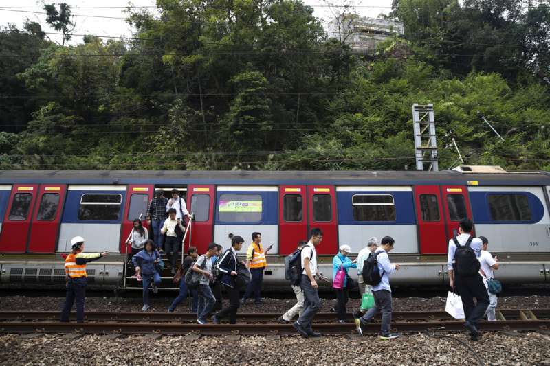 由於列車電纜遭到干擾、鐵軌附近也被投擲雜物,香港列車被迫停駛,乘客只能徒步走到車站。(美聯社) 由於列車電纜遭到干擾、鐵軌附近也被投擲雜物,香港列車被迫停駛,乘客只能徒步走到車站。(美聯社)