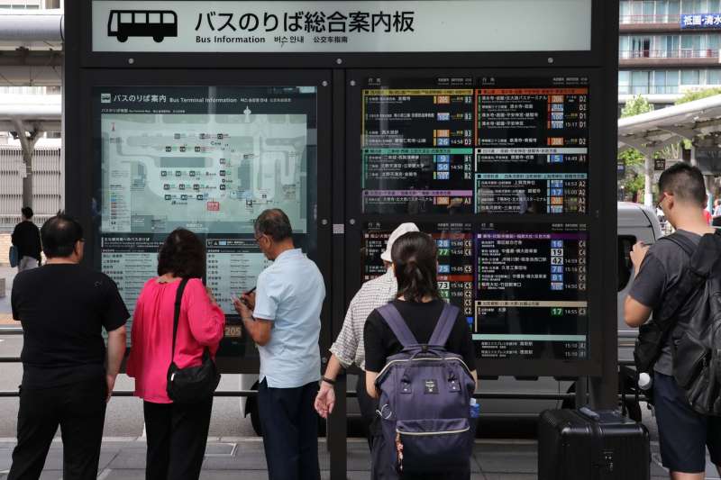 遊客在京都站前，看公車線路指南。（圖片取自nippon.com）