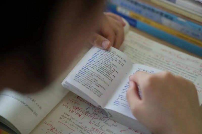 姜萍靠著一本英漢小詞典，自學全英文的《偏微分方程》。（取自央視新聞）