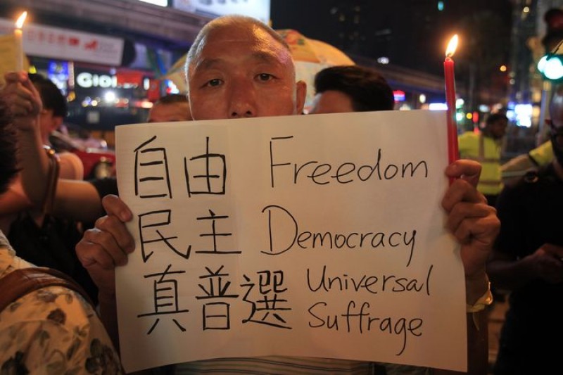 香港佔中民眾29日拿著紙板,寫著自由民主真普選。(美聯社)
