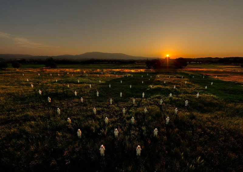 夕陽下超過30位塗白了臉的演員集體縝密地做著相同動作,有如天體移動,更像亡魂昇華,令人震撼。(圖/國家表演藝術中心衛武營營運推動小組提供) 夕陽下超過30位塗白了臉的演員集體縝密地做著相同動作,有如天體移動,更像亡魂昇華,令人震撼。(圖/國家表演藝術中心衛武營營運推動小組提供)