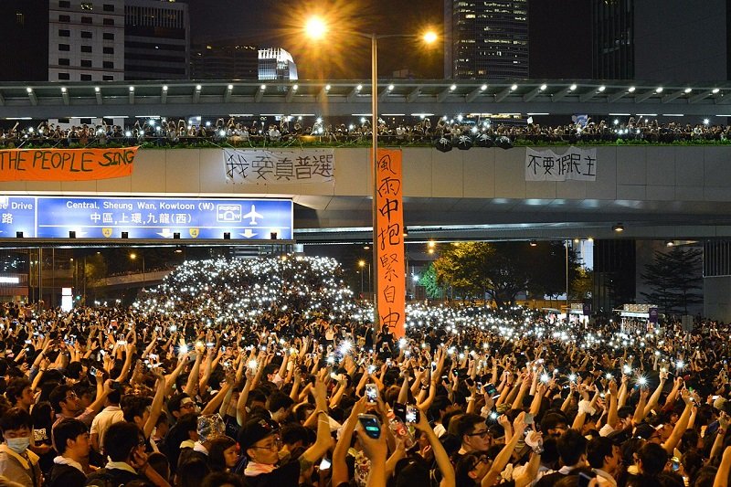 警方採取武力驅散後,數以萬計市民佔領金鐘主幹道,並亮起手機燈光。人潮經後方夏慤道天橋延伸至干諾道中。(維基百科) 警方採取武力驅散後,數以萬計市民佔領金鐘主幹道,並亮起手機燈光。人潮經後方夏慤道天橋延伸至干諾道中。(維基百科)