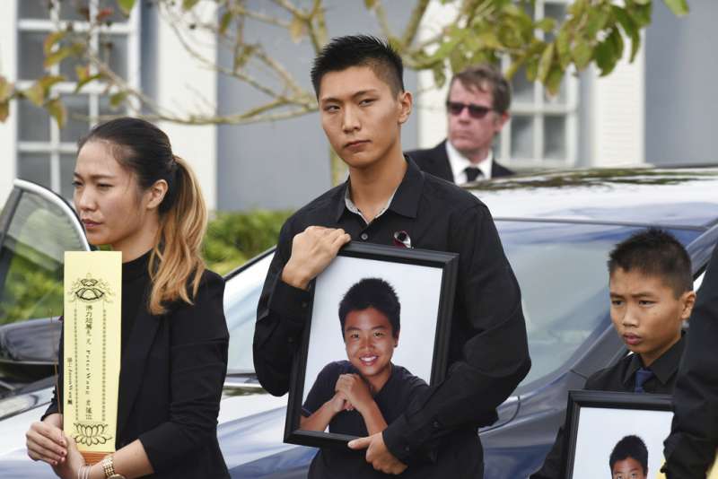 佛州校園槍擊案的15歲華裔受害者Peter Wang出殯,哥哥與弟弟分別捧著他的遺照。(美聯社) 佛州校園槍擊案的15歲華裔受害者Peter Wang出殯,哥哥與弟弟分別捧著他的遺照。(美聯社)