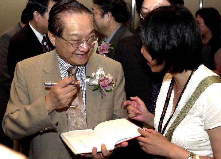 這是2001年7月22日,金庸(左)在2001香港書展上為讀者簽名留念。(新華社) 這是2001年7月22日,金庸(左)在2001香港書展上為讀者簽名留念。(新華社)