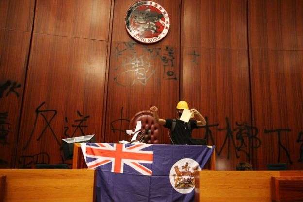 示威者在香港立法會會議廳塗污區徽,展示港英旗幟。(BBC中文網) 示威者在香港立法會會議廳塗污區徽,展示港英旗幟。(BBC中文網)