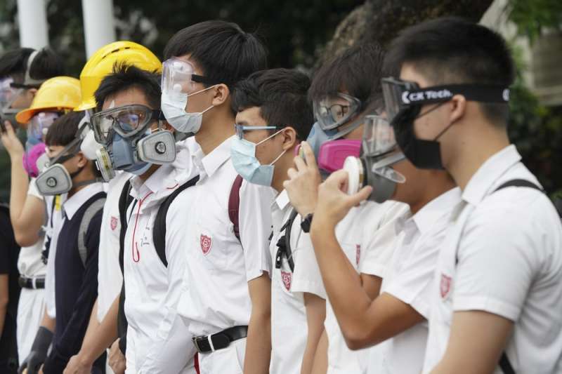 香港「反送中」運動,中學生牽起人鍊,不忘戴上防毒面具或口罩象徵抵抗警察暴力。(AP) 香港「反送中」運動,中學生牽起人鍊,不忘戴上防毒面具或口罩象徵抵抗警察暴力。(AP)