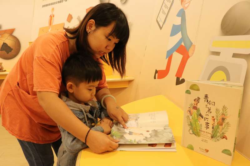 媽媽和小朋友迫不及待翻閱《青銅兄弟的故事》，看的津津有味。  (圖/新北市十三行博物館提供)     