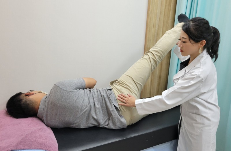 患者有下背痛併骨盆歪斜情形,醫師檢查患者肌肉協調程度,並指導病患如何訓練臀中肌運動。(圖/方詠騰攝) 患者有下背痛併骨盆歪斜情形,醫師檢查患者肌肉協調程度,並指導病患如何訓練臀中肌運動。(圖/方詠騰攝)